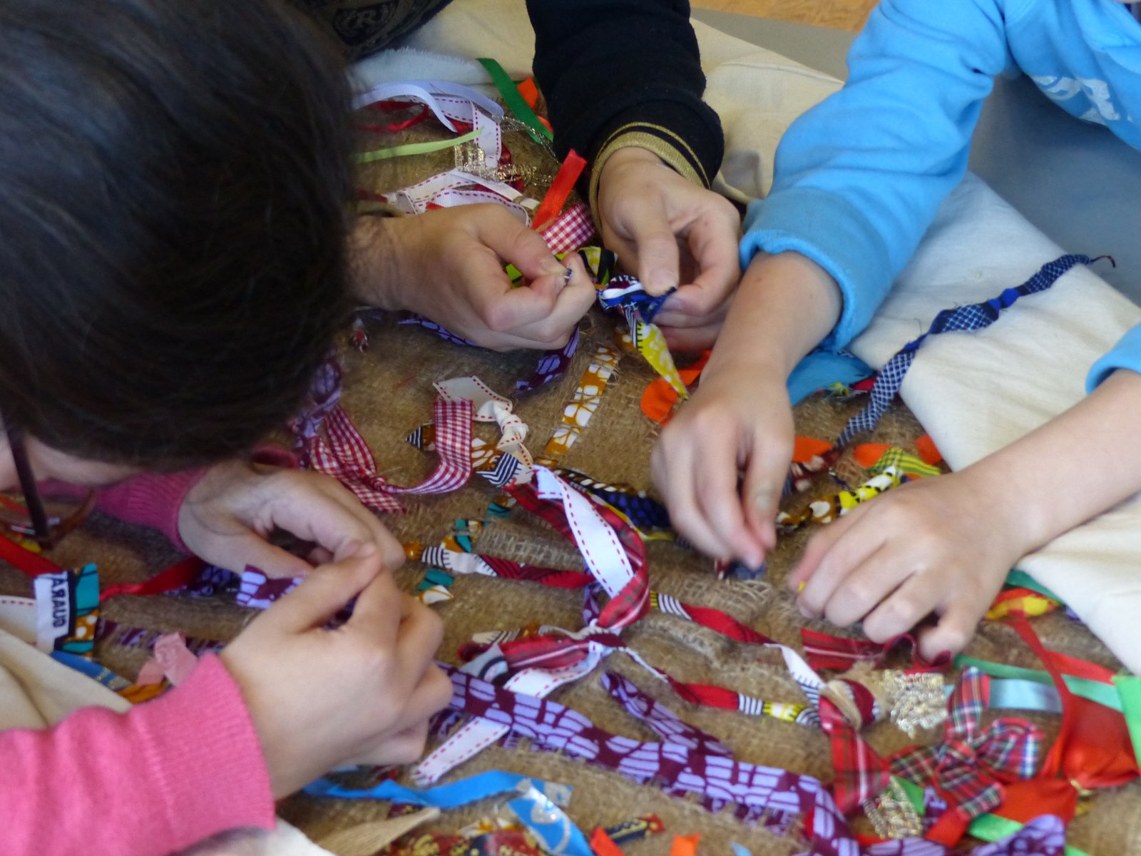Enfants qui accrochent des rubans sur de la toile de jute