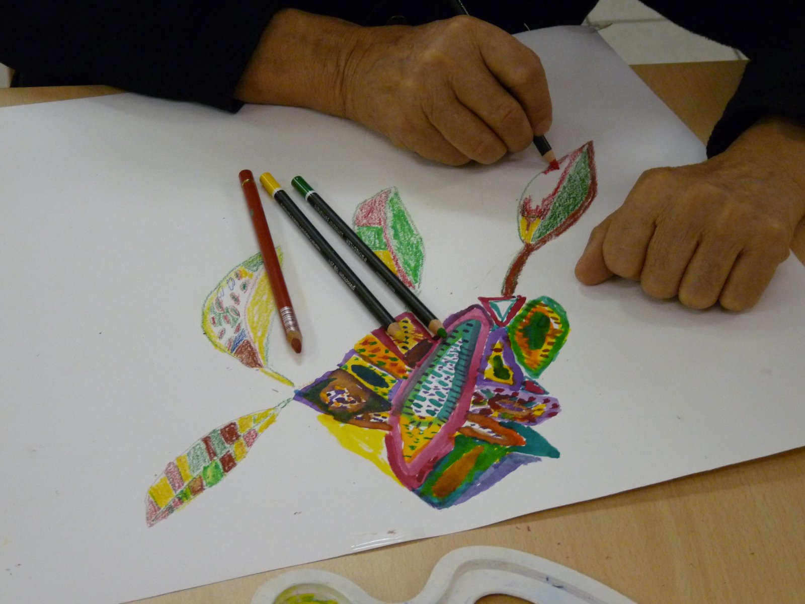 Mains d'une personne qui colorie au crayons de couleurs